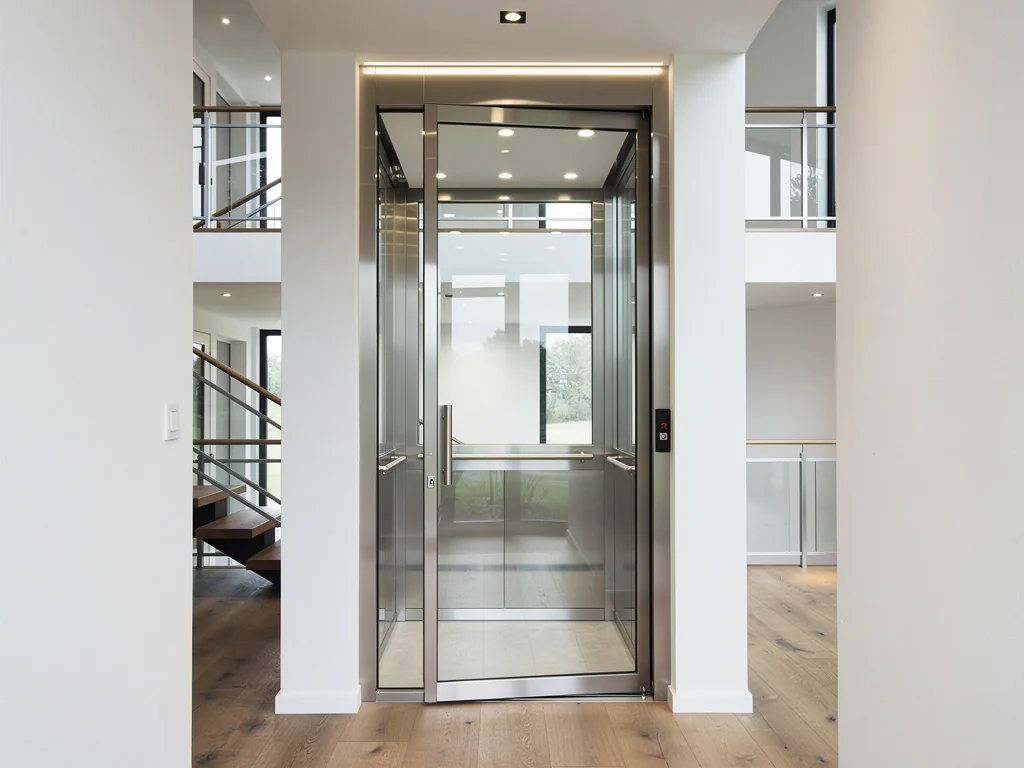 Petit ascenseur de maison à porte vitrée reliant deux niveaux d'un logement